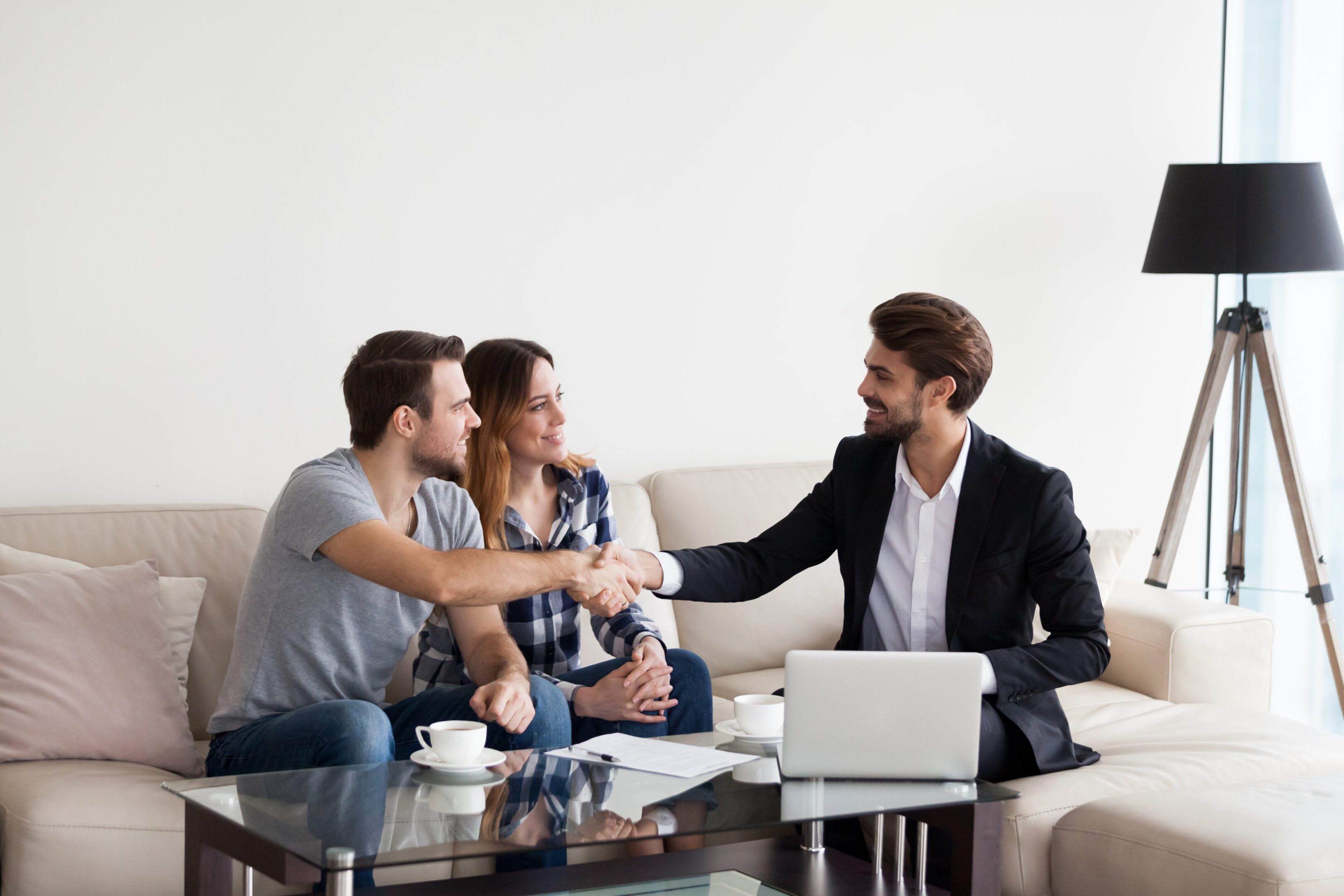 Young couple, family at meeting with Real Estate Agent, interior designer, decorator, landlord making deal. Husband handshaking with man in suit. Concept of meeting with client, customer