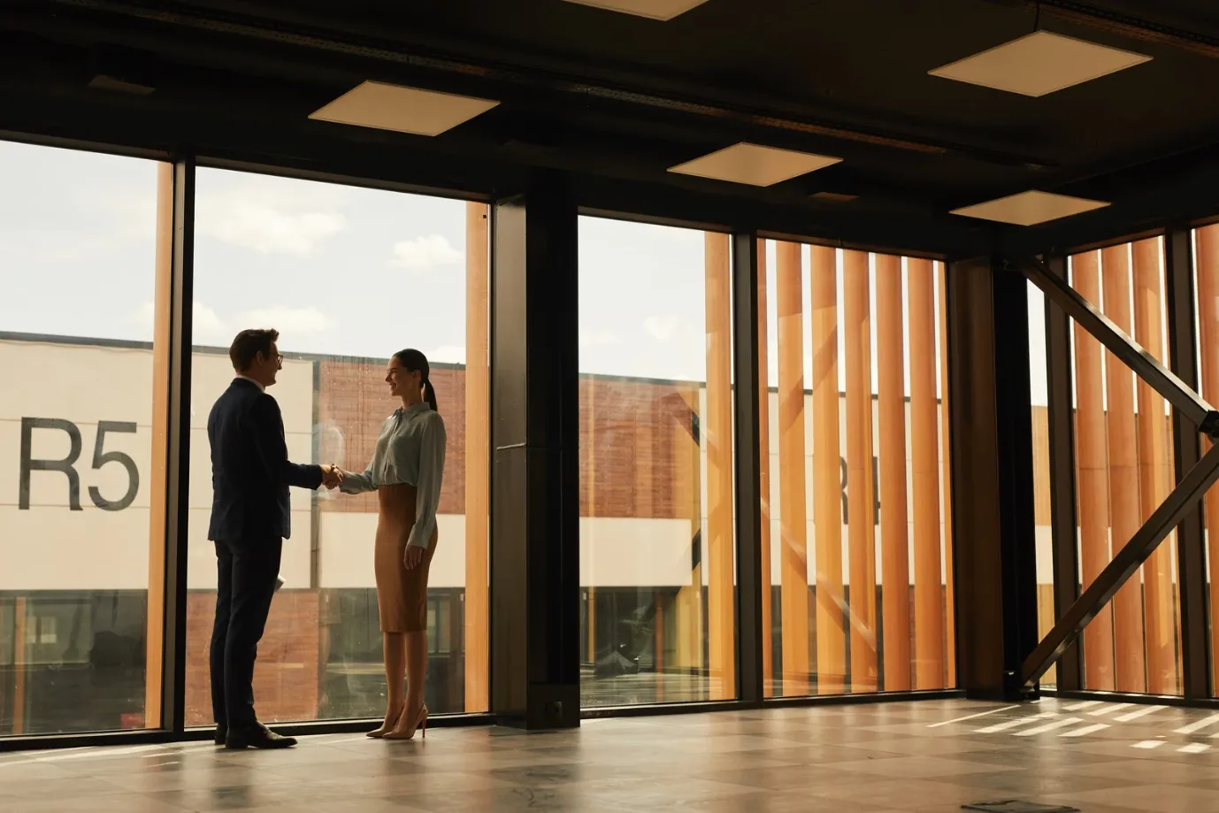 Two business professionals shaking hands in a modern commercial office building in Ottawa after finalizing a property deal.
