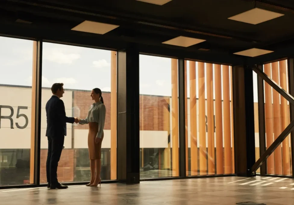 Two business professionals shaking hands in a modern commercial office building in Ottawa after finalizing a property deal.